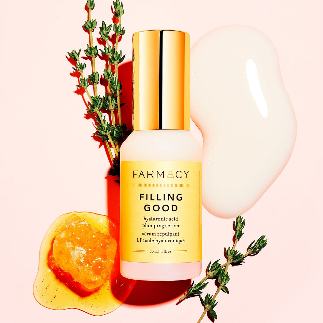 A bottle of Farmacy's Filling Good Mini laying in front of a smear of the serum and vegan collagen peptides