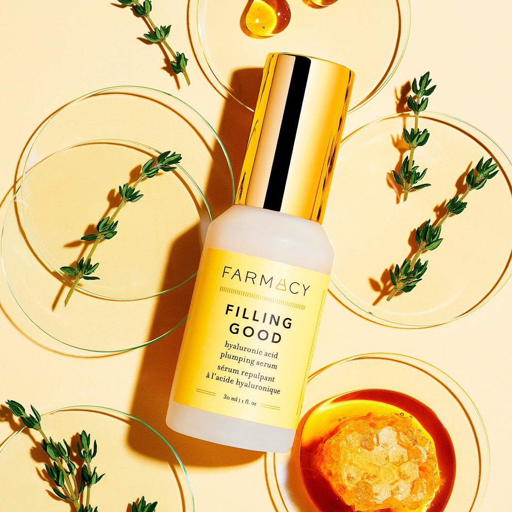 A bottle of Farmacy's Filling Good Mini laying in front of its ingredients