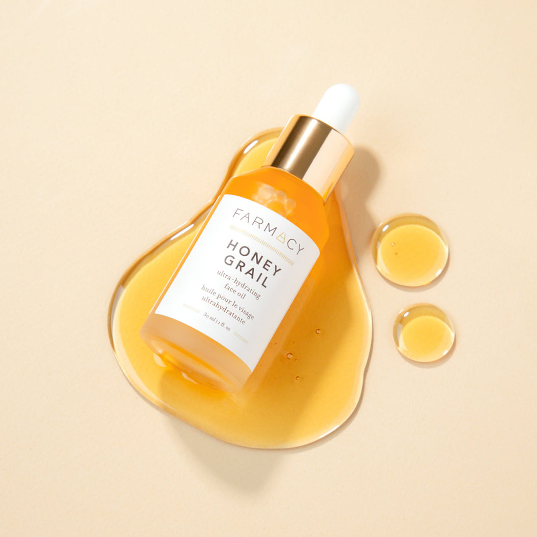 A bottle of Farmacy's Honey Grail laying on top of top of a smear of the antioxidant facial oil