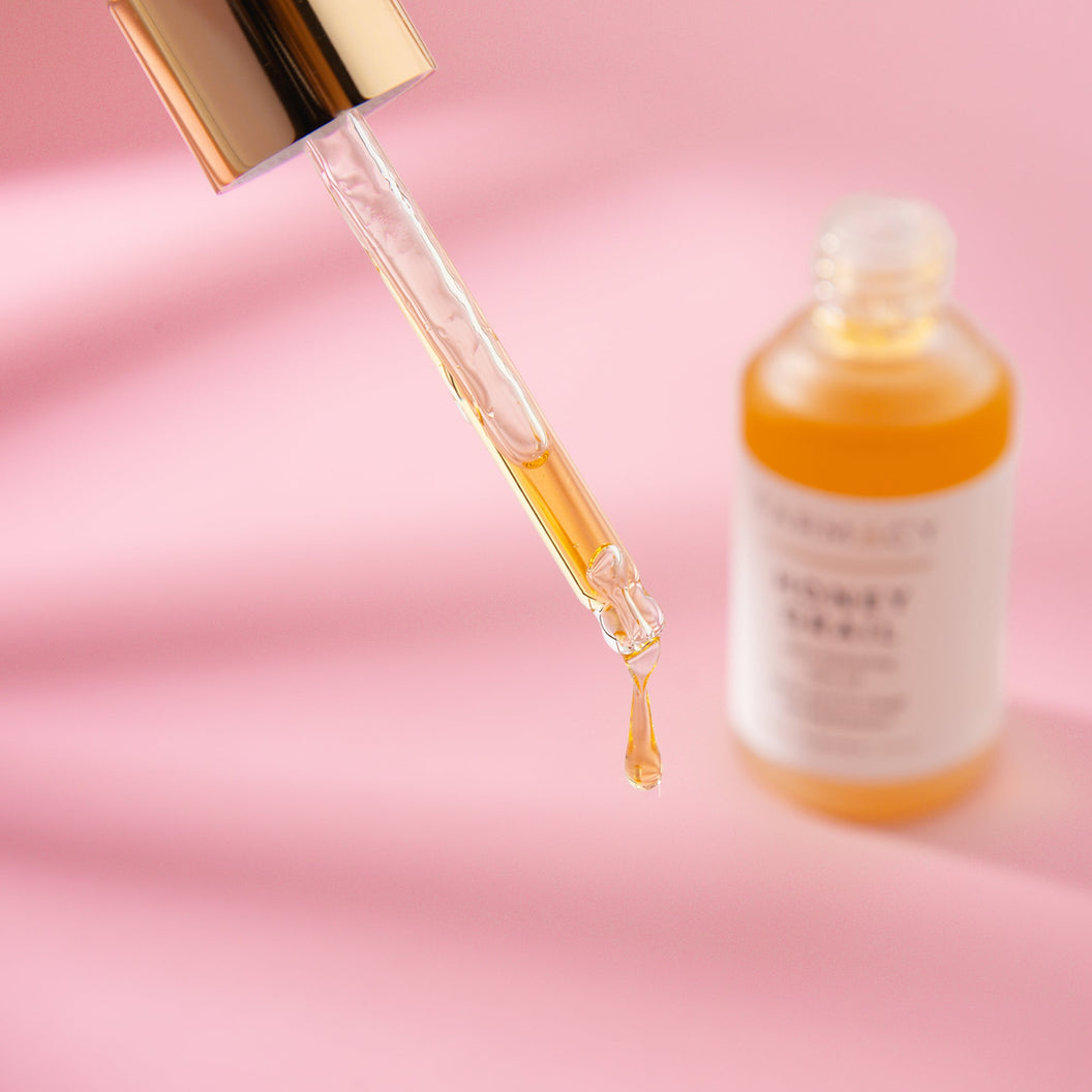 A bottle of Farmacy's Honey Grail with its contents being squeezed out of a dropper