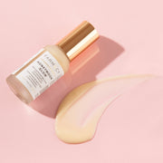  A bottle of Farmacy's Honeymoon Glow laying next to a smear of the 14% AHA resurfacing night serum