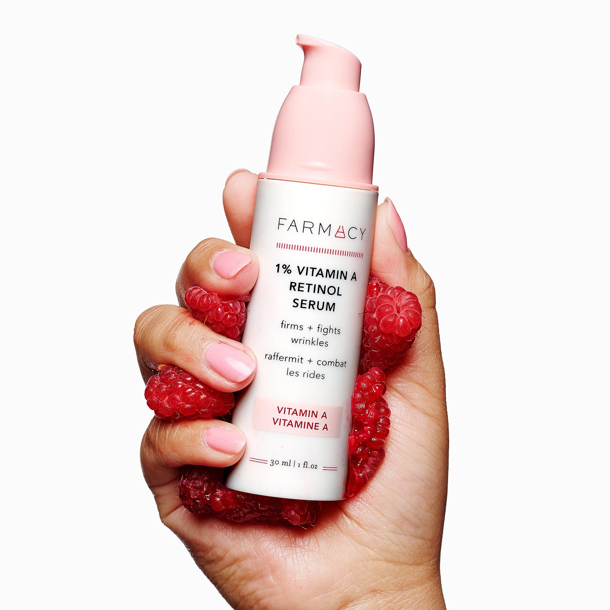 1% Vitamin A Retinol Serum packaging in its cylinder container with the cap off in the hands of a model with raspberries around it