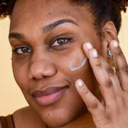 A woman applying Farmacy's Filling Good Mini Hyaluronic Acid Plumping Serum to her face