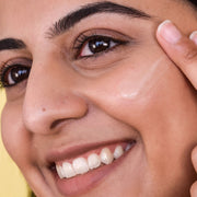 A woman applying a smear of Farmacy's Filling Good Mini Hyaluronic Acid Plumping Serum to her face
